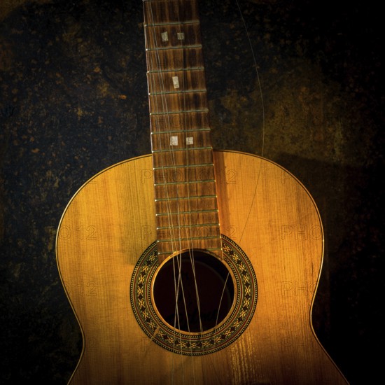 This classical guitar, resting against a dark brown backdrop, features broken strings that highlight its age and character, inviting reflection on its musical journey and stories