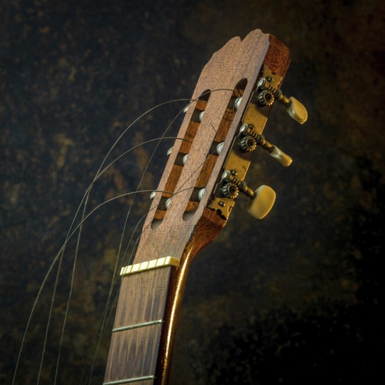 A classical guitar is positioned prominently, showcasing its intricate wooden design and broken strings. The warm brown backdrop highlights the guitar's rustic charm