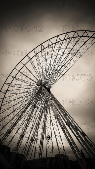A maintenance worker is seen climbing the structure of a ferris wheel that features vibrant lights. The sky is a soft hue, indicating twilight as the worker ensures safety