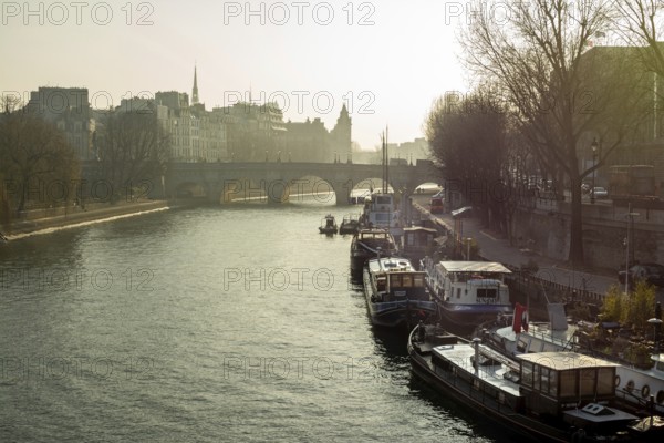 Barges float calmly on the river Seine, surrounded by historic Parisian architecture under soft morning light. The serene atmosphere highlights the beauty of the Ile-de-France region. Paris. France