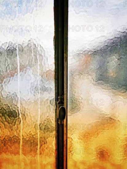 How sunlight interacts with a textured glass window, creating a mosaic of colors and reflections during sunset. The warm tones contrast beautifully with cool hues