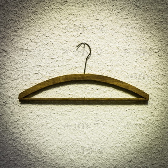 Wooden hangers are displayed against a textured light wall, highlighting a minimalist approach to clothing organization in an indoor closet area, suitable for modern decor
