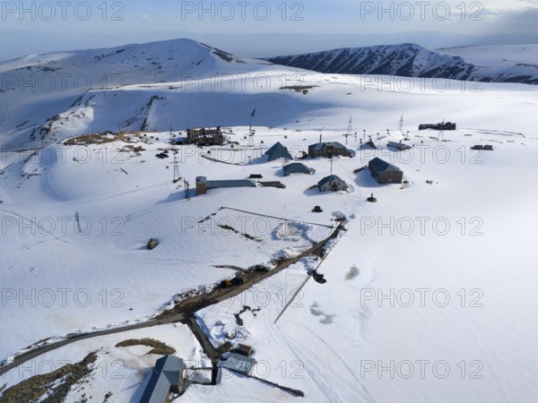 Spacious huts in snow-covered mountains with masts under a clear sky, aerial view, Aragaz, Aragac, Alagyaz, extinct stratovolcano, 4090 m, Aragazotn, Shirak, Armenia