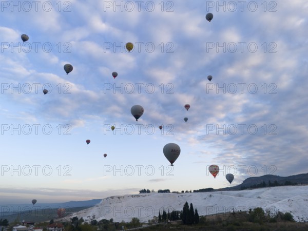 Hot air balloons float over a picturesque landscape under a cloudy sky, aerial view, Pamukkale, Denizli, Anatolia, Turkey