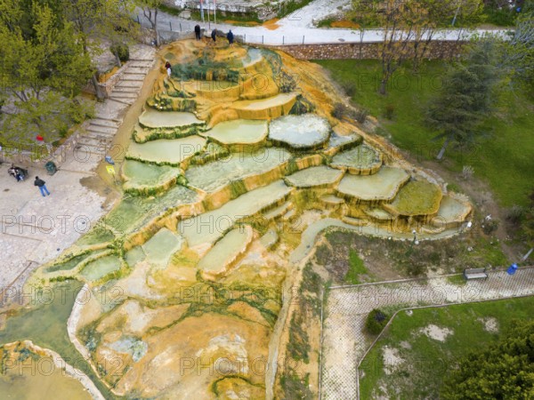 Multicoloured natural mineral terraces with water accumulations in a park landscape, aerial view, Karahayit Kirmizi Su, Red Spring, Pamukkale, Denizli, Turkey