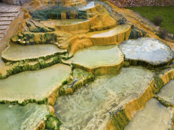 Natural mineral terraces with water accumulations and colourful rock formations, aerial view, Karahayit Kirmizi Su, Red Spring, Pamukkale, Denizli, Turkey