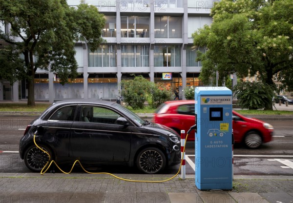 Charging station Stadtwerke Stuttgart for electric cars, charging station, e-filling station, e-mobility, charging cable leads into e-car, logo, red car behind it, motion effect, Stuttgart, Baden-Württemberg, Germany