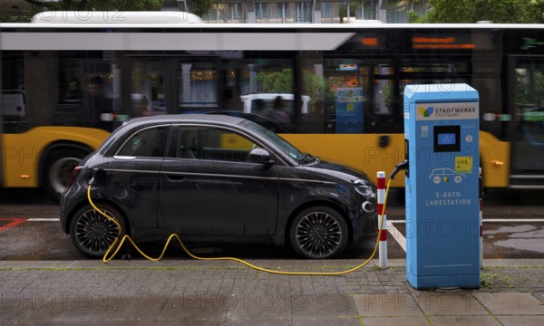 Charging station Stadtwerke Stuttgart for electric cars, charging station, e-charging station, e-mobility, charging cable leads into e-car, logo, behind it drives yellow bus, public transport, local transport, SSB, city bus, movement effect, Stuttgart, Baden-Württemberg, Germany
