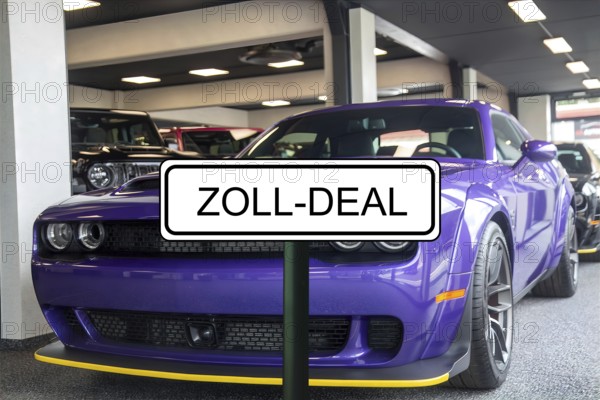 (Photomontage) Symbolic image of the customs agreement between the EU and the USA: sign with the inscription ZOLL-DEAL in front of a new Dodge at the dealership