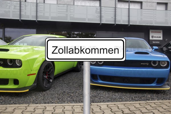 (Photomontage) Symbolic image of the customs agreement between the EU and the USA: sign with the inscription ZOLLABKOMMEN in front of new Dodge at the dealership