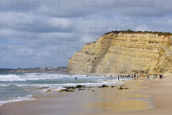 Surfers on the beach and cliffs, Praia de Porto de Mos, Algarve, Portugal