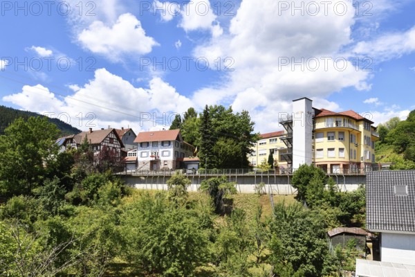 Forbach, Germany - July 12th 2025: Buildings surrounded by trees in Forbach. Scenic summer view of Black Forest town under blue sky