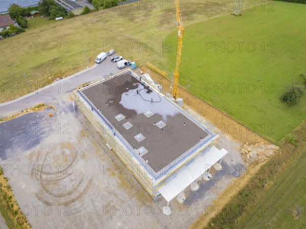 Aerial view of a building under construction with vehicles and crane on a wide field, green roof, house construction, climate neutral