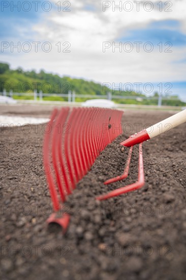 Close-up of a red rake working the soil on a roof, with nature in the background, roof greening, house construction, climate neutral