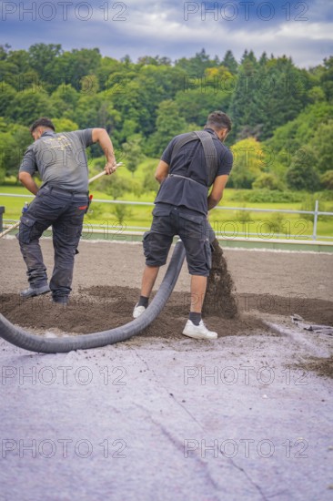 Two workers lay material with a hose on a roof on a green site, roof greening, house construction, climate neutral