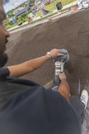 Close-up of a worker using a tool on a floor, roof greening, house construction, climate neutral