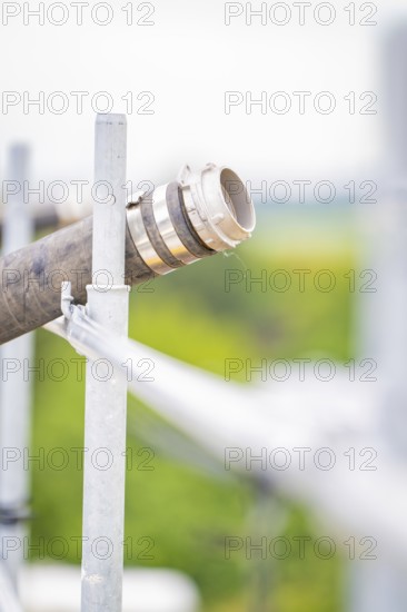 Metal pipe with mounting in blurred, green background, roof greening, house construction, climate neutral
