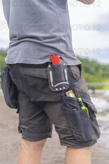 Man with tool bag outdoors, roof greening, house construction, climate neutral