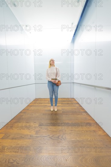 Woman standing in a modern lift with bright, minimalist design and wooden floor, Frieder Burda Museum, Baden Baden, Germany