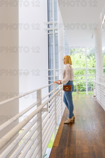 A woman stands at a railing and looks through a large window at the surroundings, Frieder Burda Museum, Baden Baden, Germany