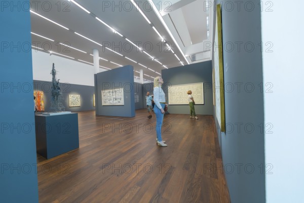 People looking at paintings in a modern art gallery with wooden floor and dark walls, Frieder Burda Museum, Baden Baden, Germany