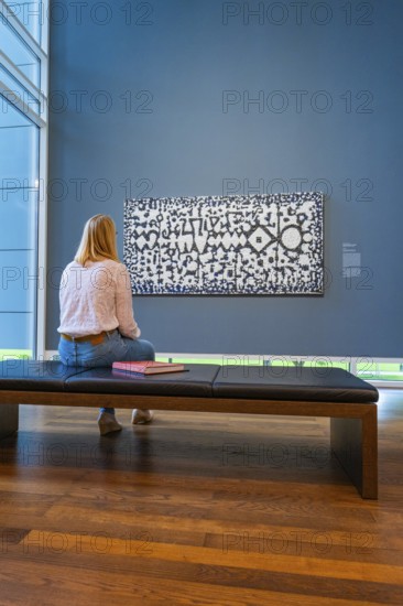 Woman sitting on a bench and looking at a work of art on a blue wall, Frieder Burda Museum, Baden Baden, Germany
