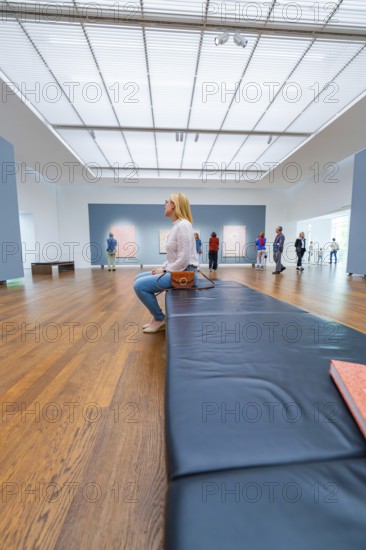 Visitors sit on a bench in a gallery and look at the works of art on display, Frieder Burda Museum, Baden Baden, Germany