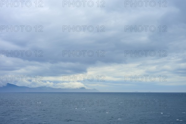 Wide sea with cloudy sky and distant mountains on the horizon, summer, Cook Strait, North Island, South Island, New Zealand