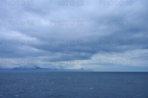 Sweeping views of the sea and distant clouds over the mountains on the horizon, summer, Cook Strait, North Island, South Island, New Zealand