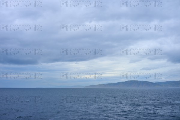 View of the sea and a distant coastline under a cloudy sky, summer, Cook Strait, North Island, South Island, New Zealand
