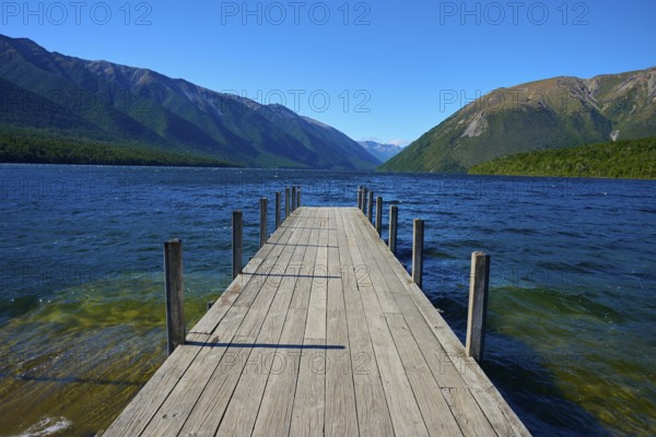 A long wooden jetty juts out into a calm lake, surrounded by mountains under a clear blue sky, summer, Lake Rotoiti, Saint Arnaud, Tasman Region, South Island, New Zealand