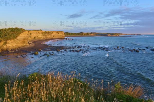 Idyllic coastal scene at sunrise with waves, beach and cliffs, summer, Opunake, Taranaki, North Island, New Zealand