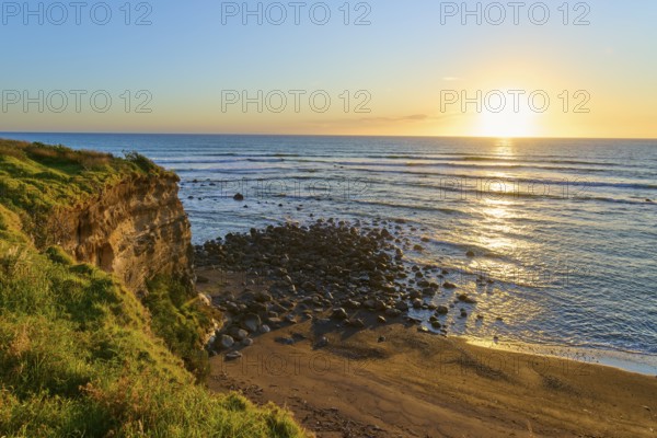 Sunset landscape with rocks and beach, warm colours dominate the scene, summer, Opunake, Taranaki, North Island, New Zealand