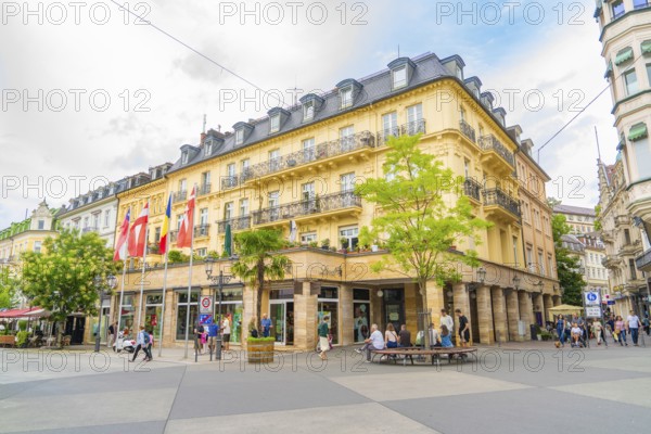 Corner building with balconies and flags, lively with people, urban atmosphere, Baden Baden, Germany