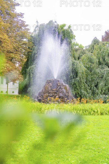 A tall fountain in a green park with lush vegetation and a relaxed atmosphere, Baden Baden, Germany