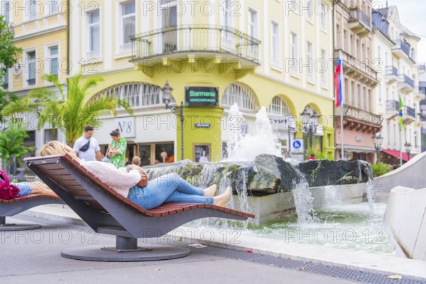 People relaxing on deckchairs at the fountain in the city, Baden Baden, Germany
