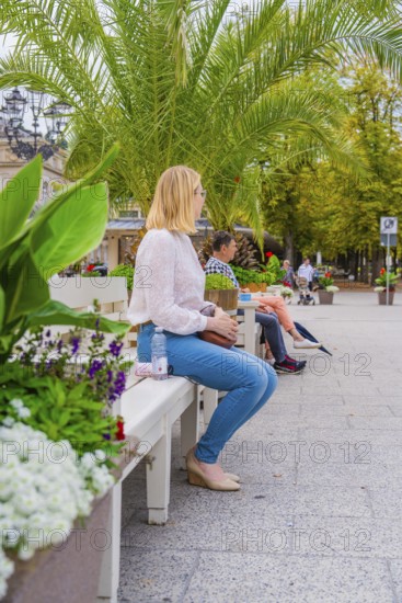 People sitting on a park bench surrounded by green plants and trees in the city, Baden Baden, Germany