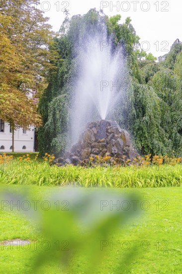 Bubbling fountain in a green park landscape, surrounded by trees and flowers, Baden Baden, Germany
