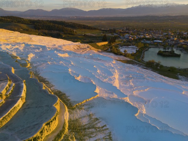 Panorama of terraces and water with mountain backdrop in the soft light of dusk, aerial view, sinter terraces, limestone sinter terraces, travertine terraces, Pamukkale, Denizli, UNESCO World Heritage Site, Anatolia, Turkey