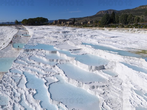 Extensive limestone sinter terraces with water and surrounding landscape in Pamukkale, aerial view, sinter terraces, limestone sinter terraces, travertine terraces, Pamukkale, Denizli, UNESCO World Heritage Site, Anatolia, Turkey