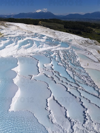 Terraces of turquoise water in white formations, mountains visible in the background under a clear sky, aerial view, sinter terraces, lime sinter terraces, travertine terraces, Pamukkale, Denizli, UNESCO World Heritage Site, Anatolia, Turkey