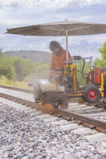 Worker welding railway track, sparks spraying, rural surroundings, grinding work on the Hermann Hesse railway, Ostelsheim, Calw district, Germany