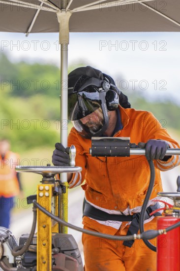 A worker in an orange suit and helmet works under an umbrella on a railway line, grinding work on the Hermann Hesse railway, Ostelsheim, district of Calw, Germany