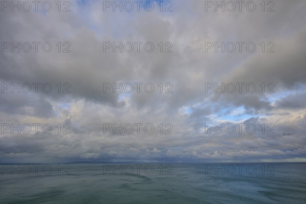Expansive cloudy sky over a calm sea, summer, Nugget Point lighthouse, Ahuriri Flat, Otago, South Island, New Zealand