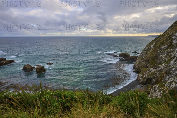 Rough sea against rocks with a cloudy sky in the background, summer, Nugget Point lighthouse, Ahuriri Flat, Otago, South Island, New Zealand