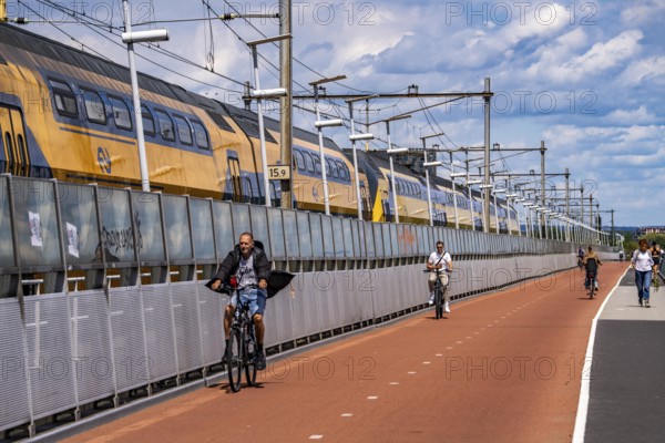 Cycle and pedestrian bridge Snelbinder Brug, over the river Waal near Nijmegen, was added to the existing railway bridge, fast cycle path connection from the city centre of Nijmegen and the new housing estates in the Waalsprong district, Netherlands