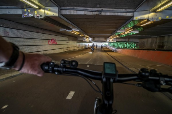 Ride your bike through the tunnel under the tracks of Utrecht Central, HBF, on the central cycle path on the Lange Viestraat, Vredenburg, in the city centre of Utrecht, lanes for pedestrians, cyclists and public transport vehicles are separated, dense cycle traffic, Netherlands