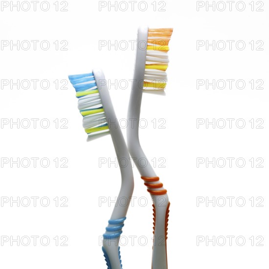 Two vibrantly colored toothbrushes stand at an angle against a plain background. They highlight the importance of dental hygiene and daily oral care routines