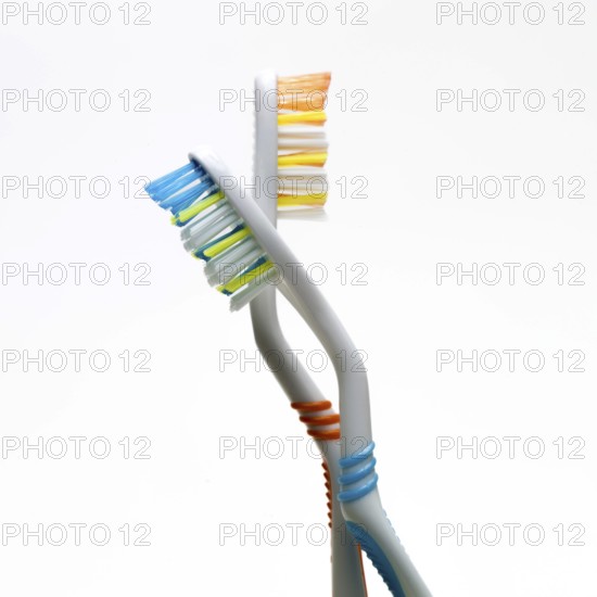 The image features two toothbrushes twisted together, highlighting their vibrant bristle colors and unique ergonomic shapes. These dental tools emphasize the importance of oral care