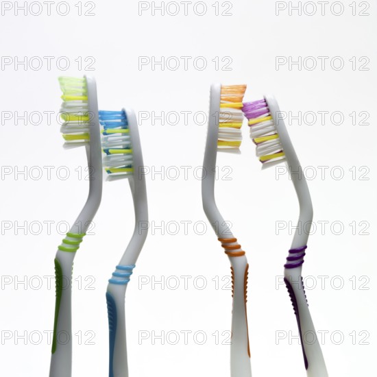 Four vibrant toothbrushes in varied colors stand side by side against a simple background, highlighting the importance of oral hygiene and daily dental care
